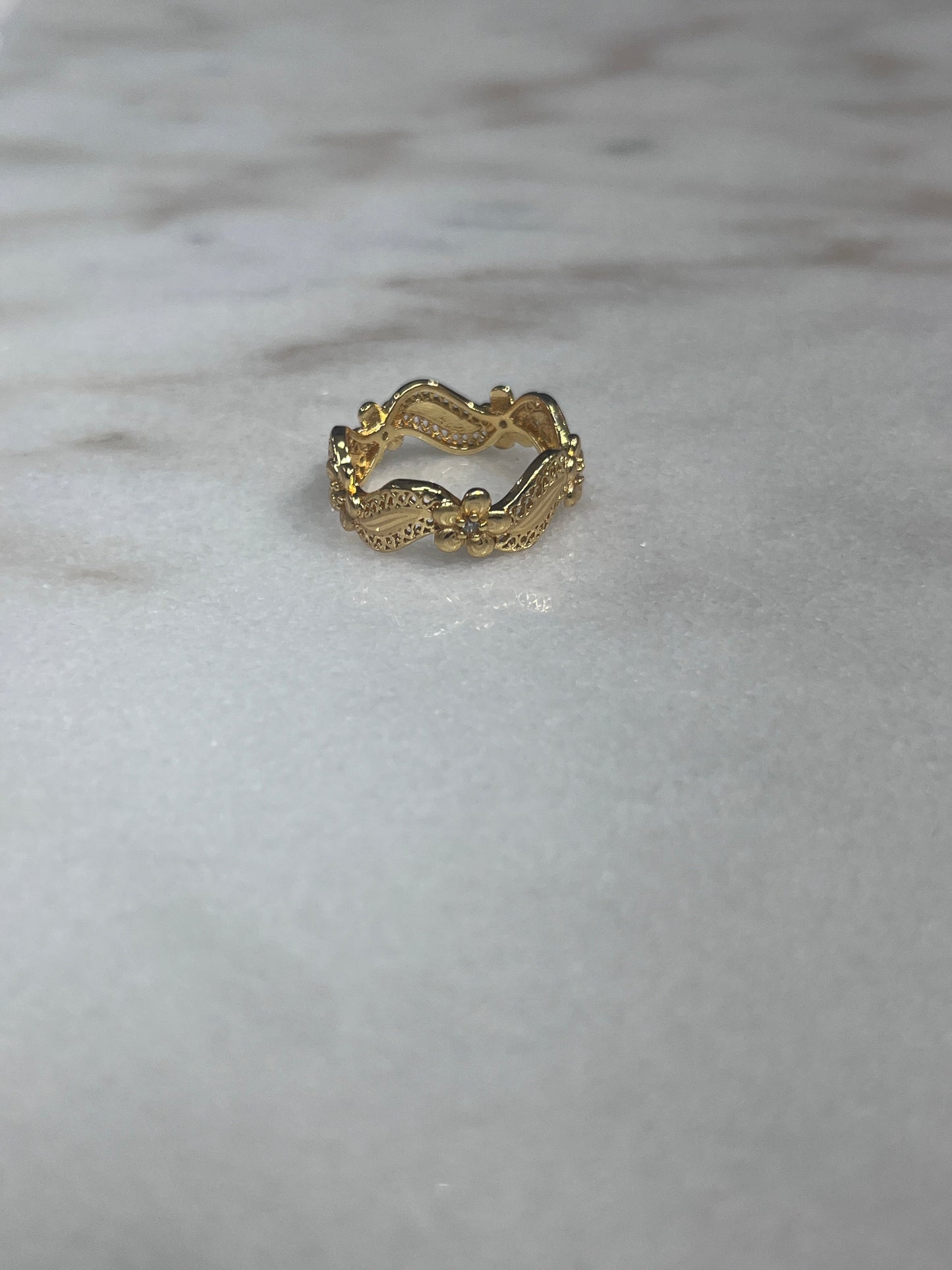 Imitated Gold Curved Ring with Flower Design by Palestinian Elegance on marble surface