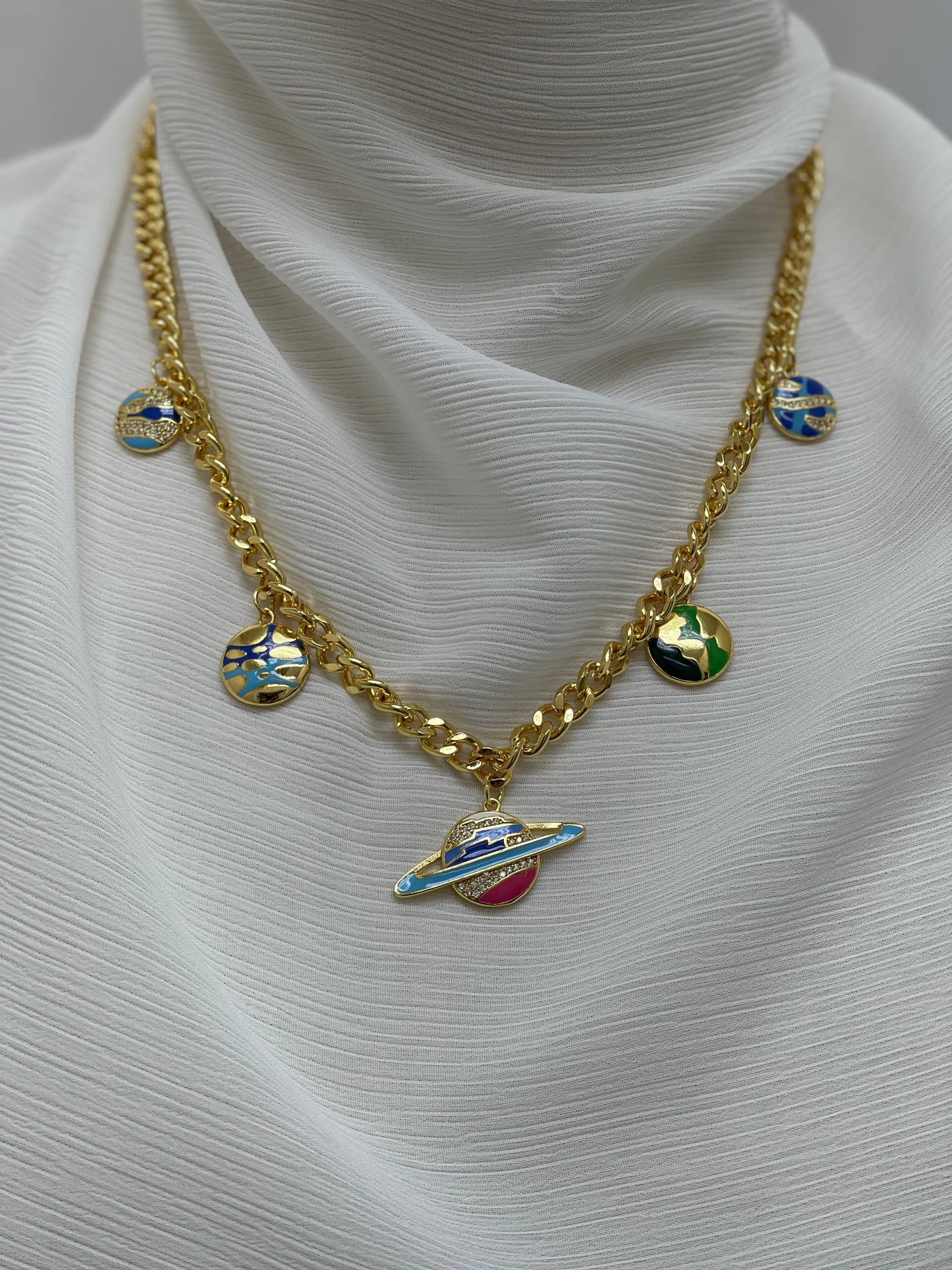 Palestinian Elegance gold chain with multicolor planet necklace and planet charms on white fabric