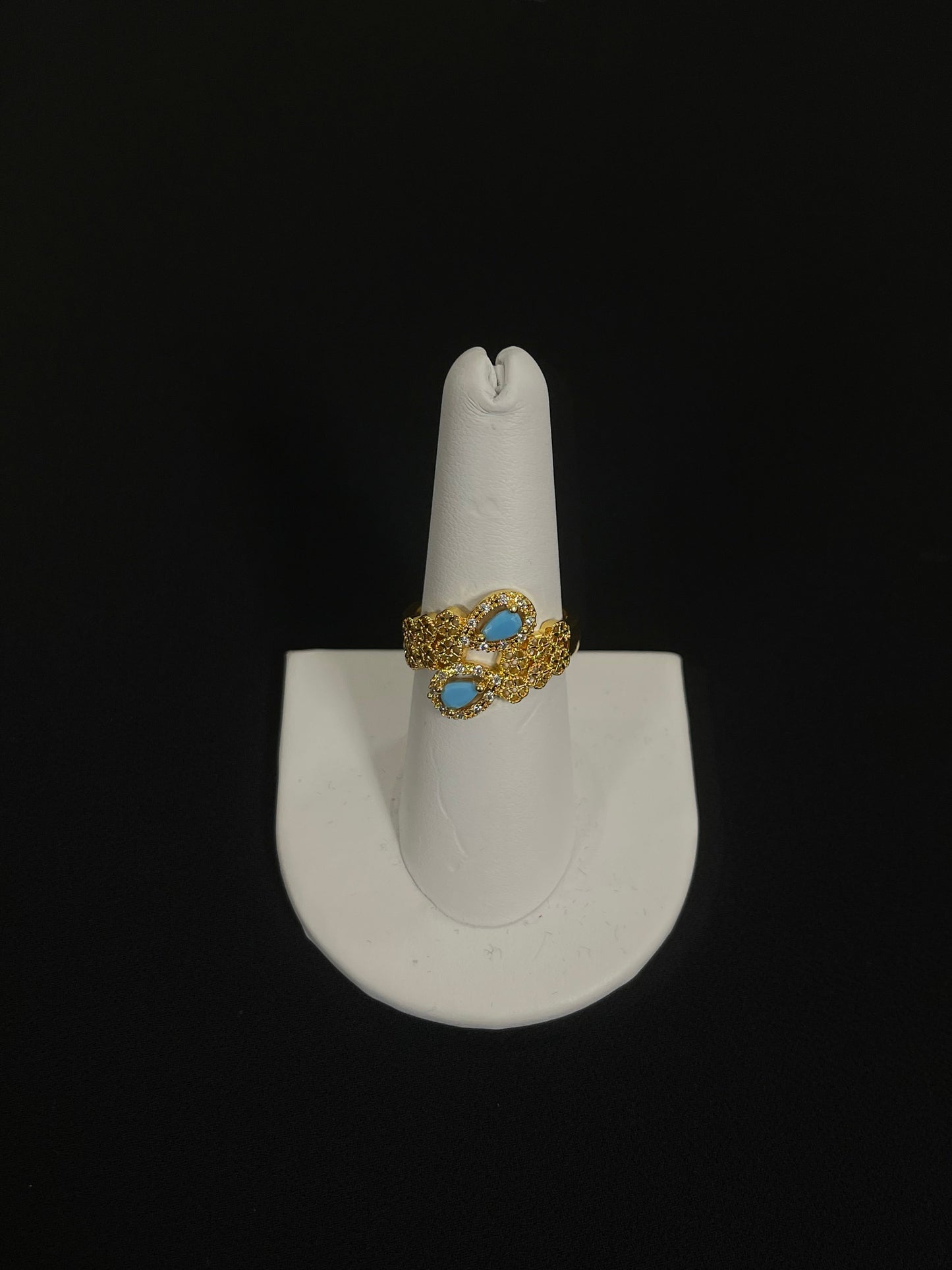 Palestinian gold jewelry set featuring a gold ring with blue stones on a white display stand