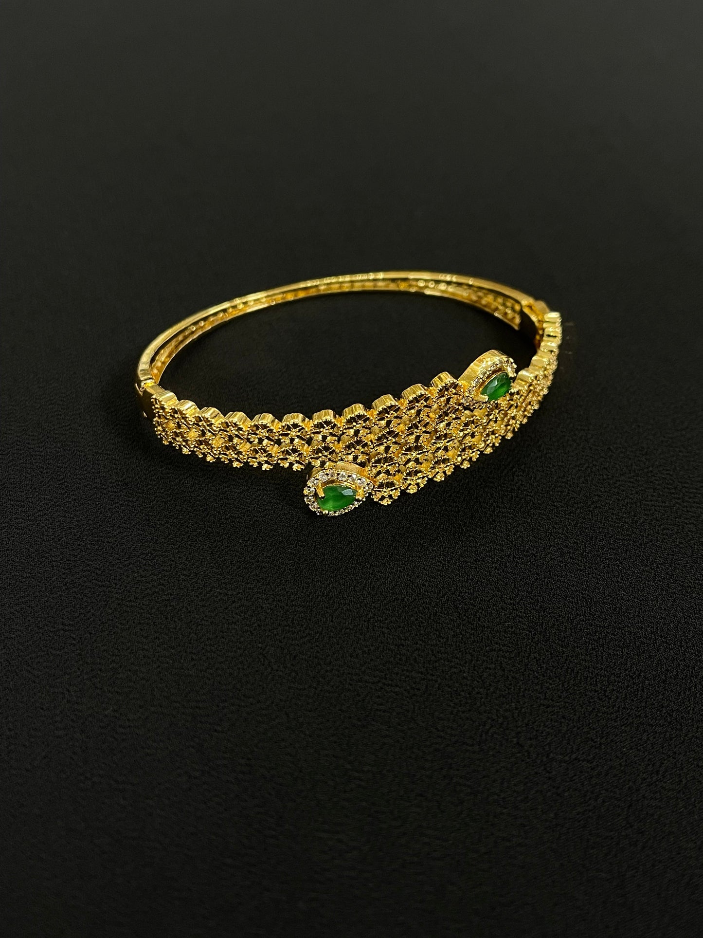 Elegant Palestinian gold jewelry set bracelet with green gemstone accents on black background