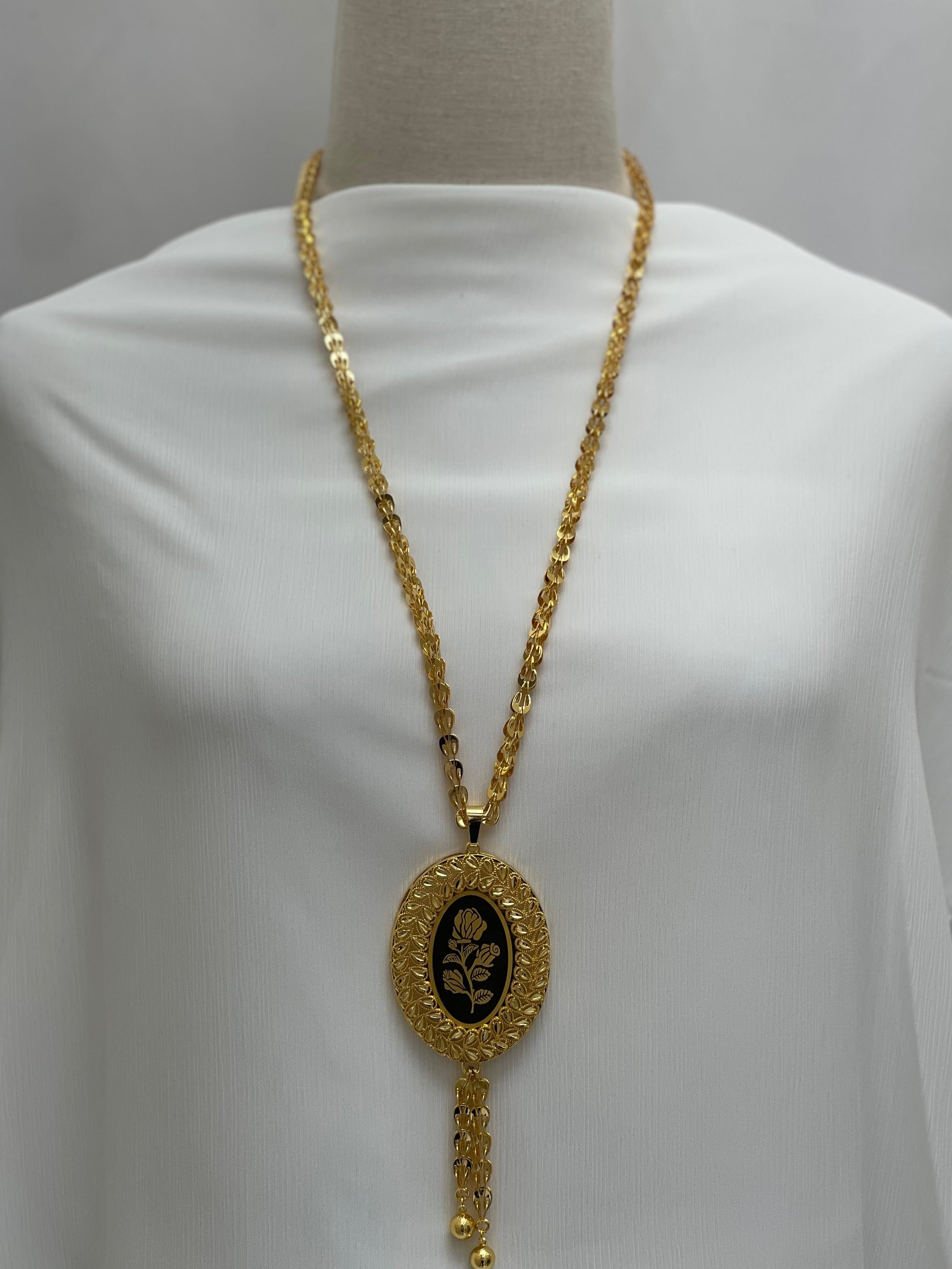 Palestinian Elegance long rose pendant necklace with gold chain and black oval pendant featuring a rose design
