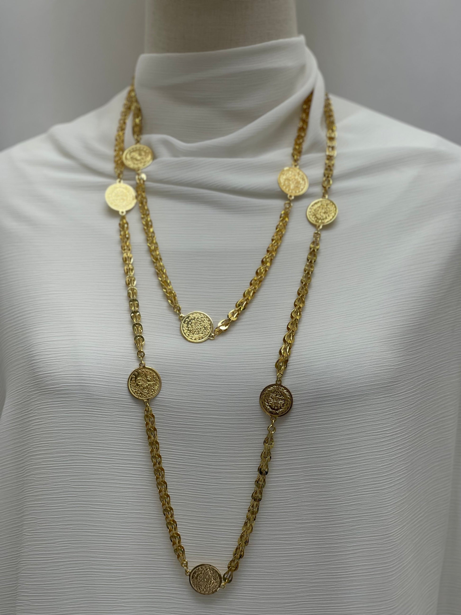 Palestinian coin necklace by Palestinian Elegance featuring gold-tone chain with round coin charms on white fabric background