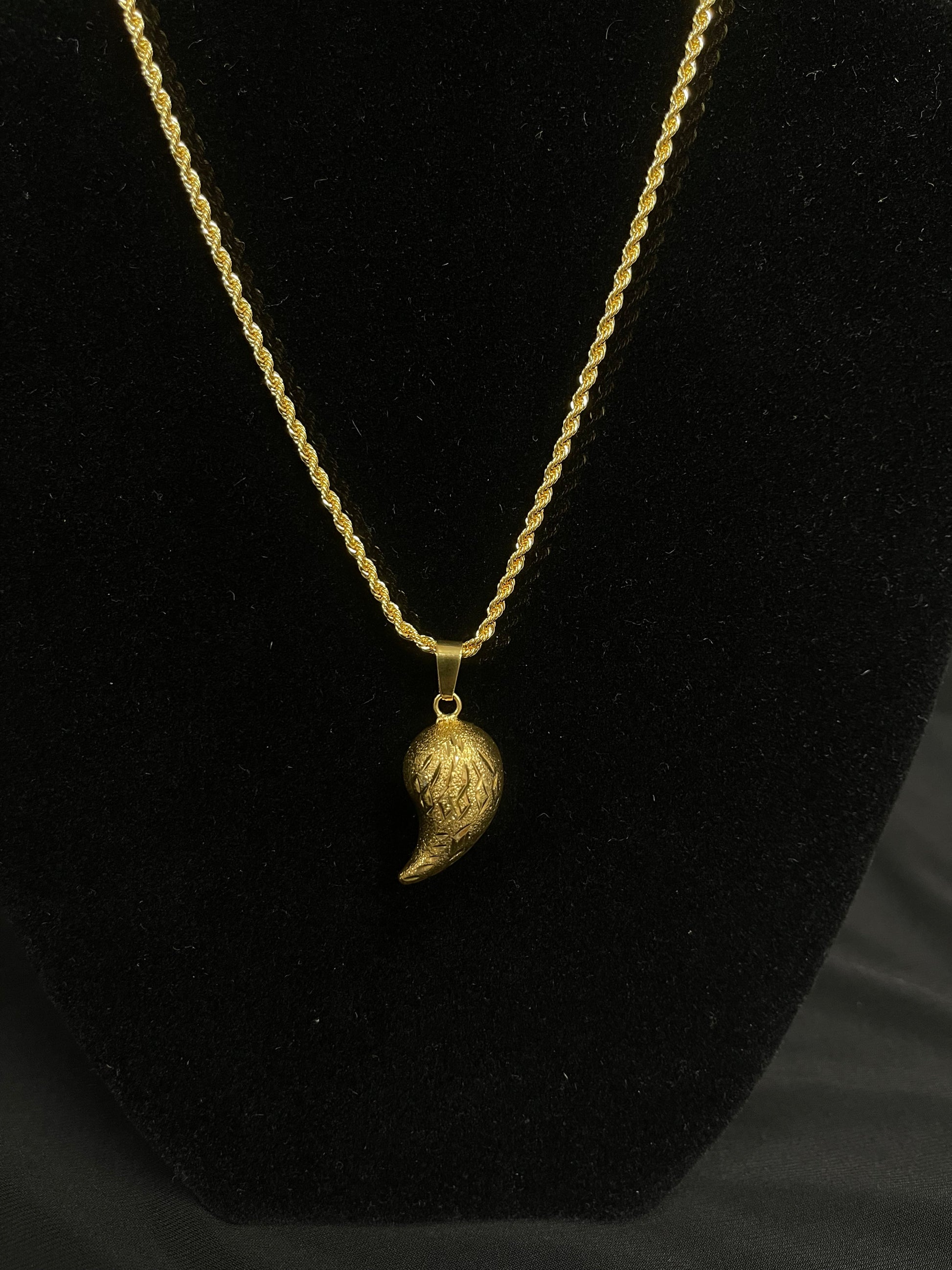 Almond shape gold pendant in imitated gold by Palestinian Elegance displayed on black stand