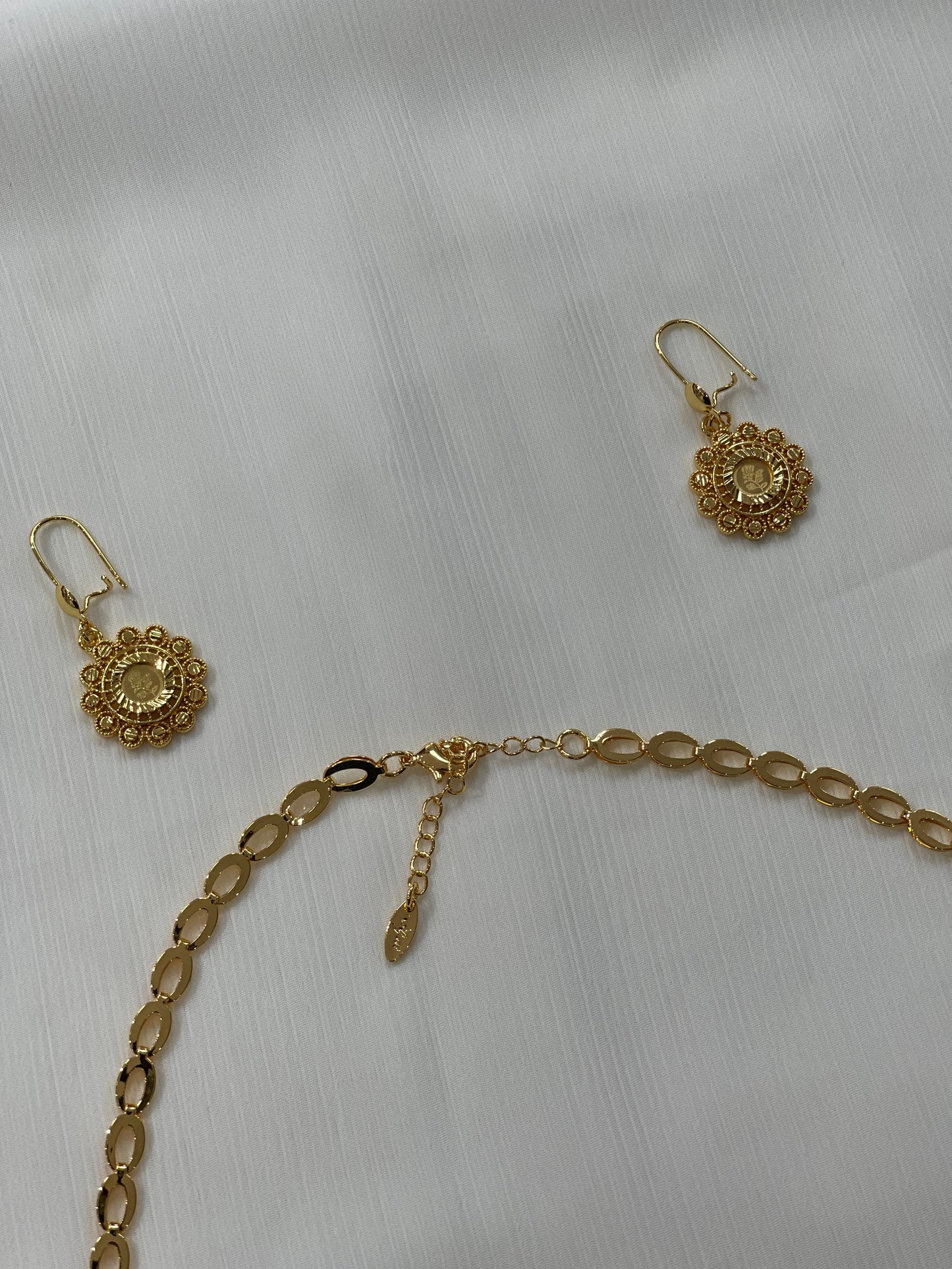 Gold jewelry set for women including intricate gold earrings and a matching linked chain necklace