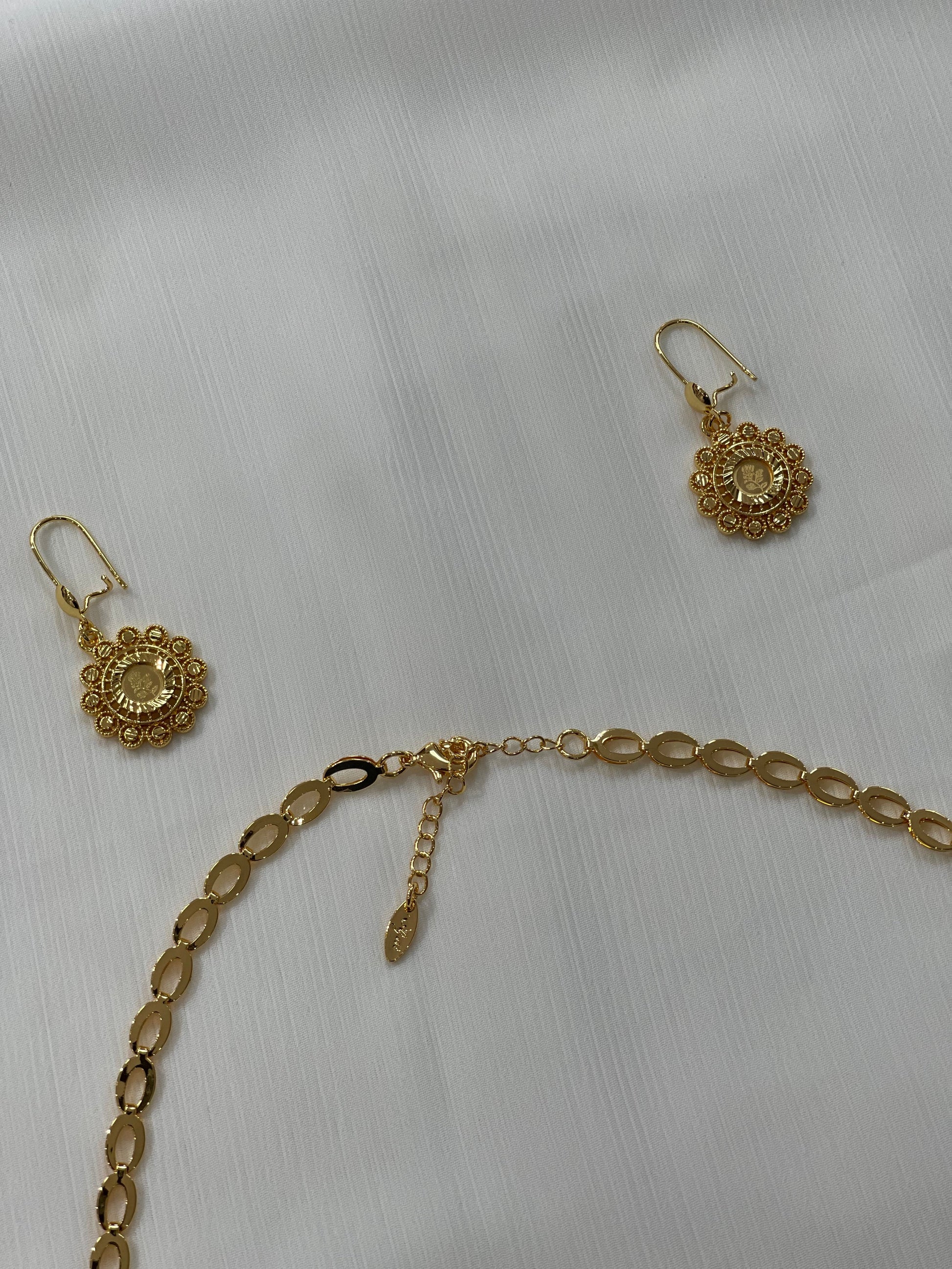 Gold jewelry set for women including intricate gold earrings and a matching linked chain necklace