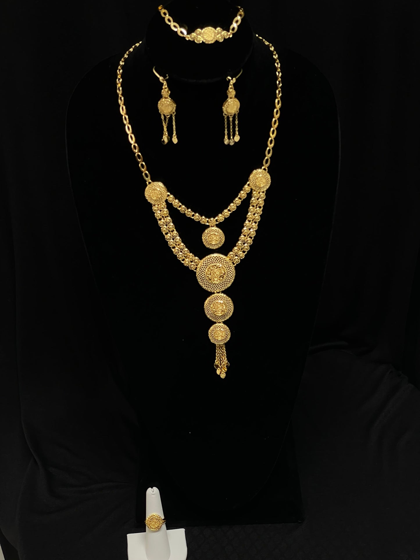 Palestinian Elegance gold layered necklace set with intricate circular pendants and matching earrings on black display