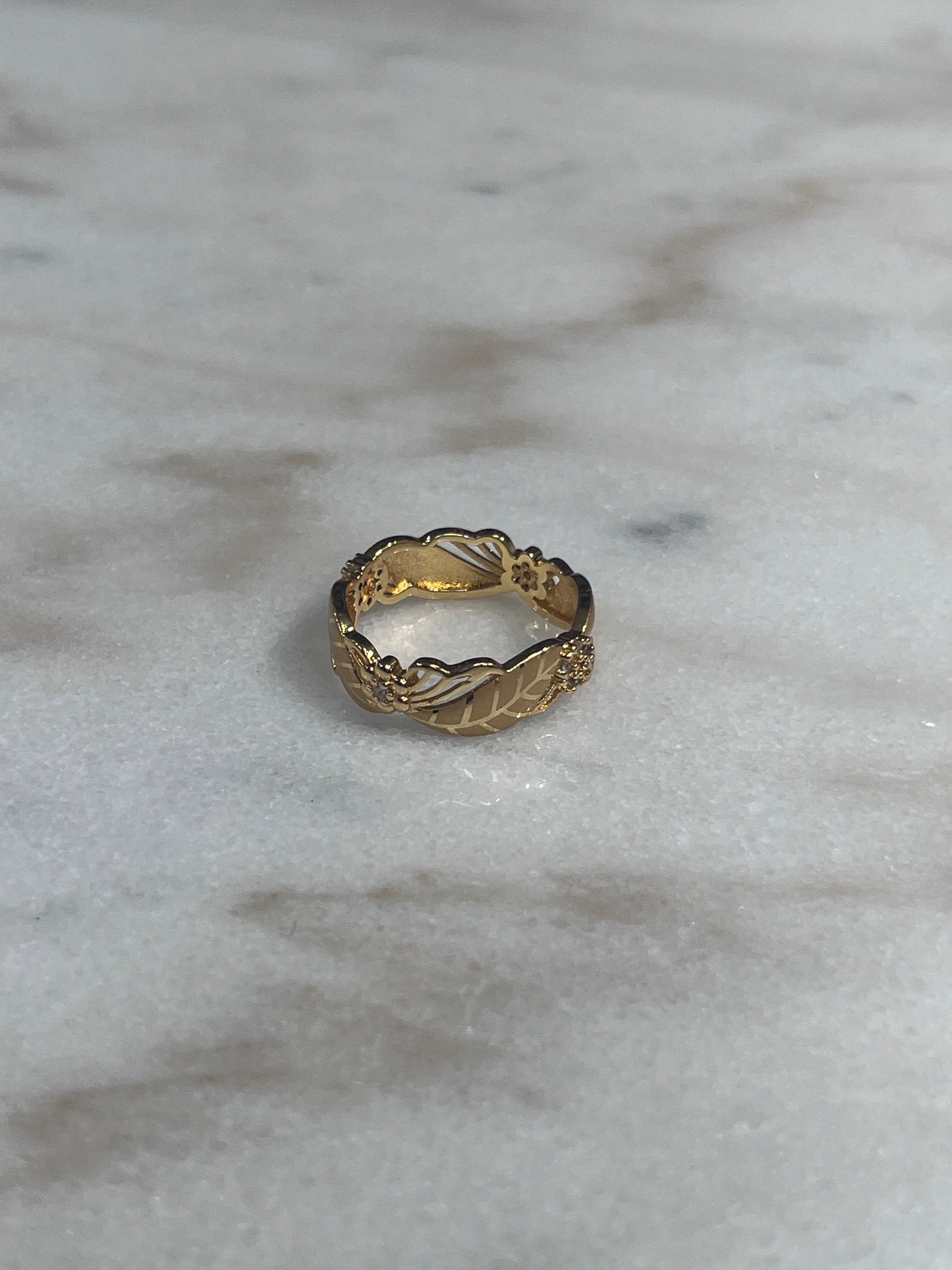 Imitated Gold Ring with Flower Design by Palestinian Elegance on marble surface
