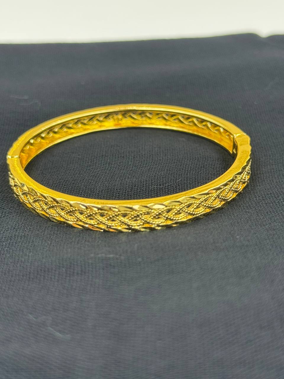 Palestinian Elegance imitation gold bangle bracelet with intricate braided design on black background
