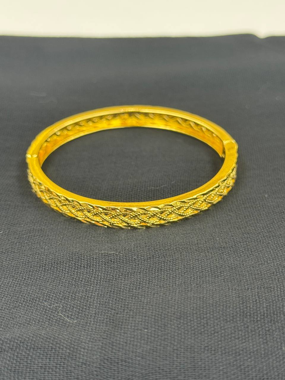 Palestinian Elegance imitation gold bangle bracelet with intricate woven design on black background