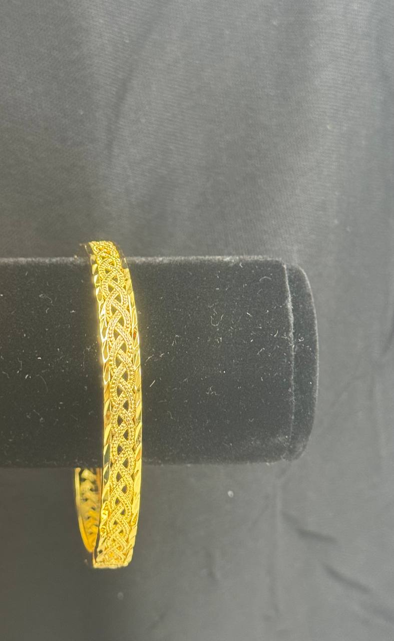 Intricately designed imitation gold bangle bracelet by Palestinian Elegance displayed on black velvet stand