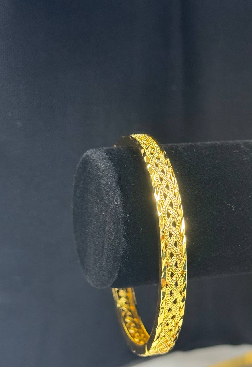 Palestinian Elegance imitation gold bangle bracelet with intricate filigree design on black display