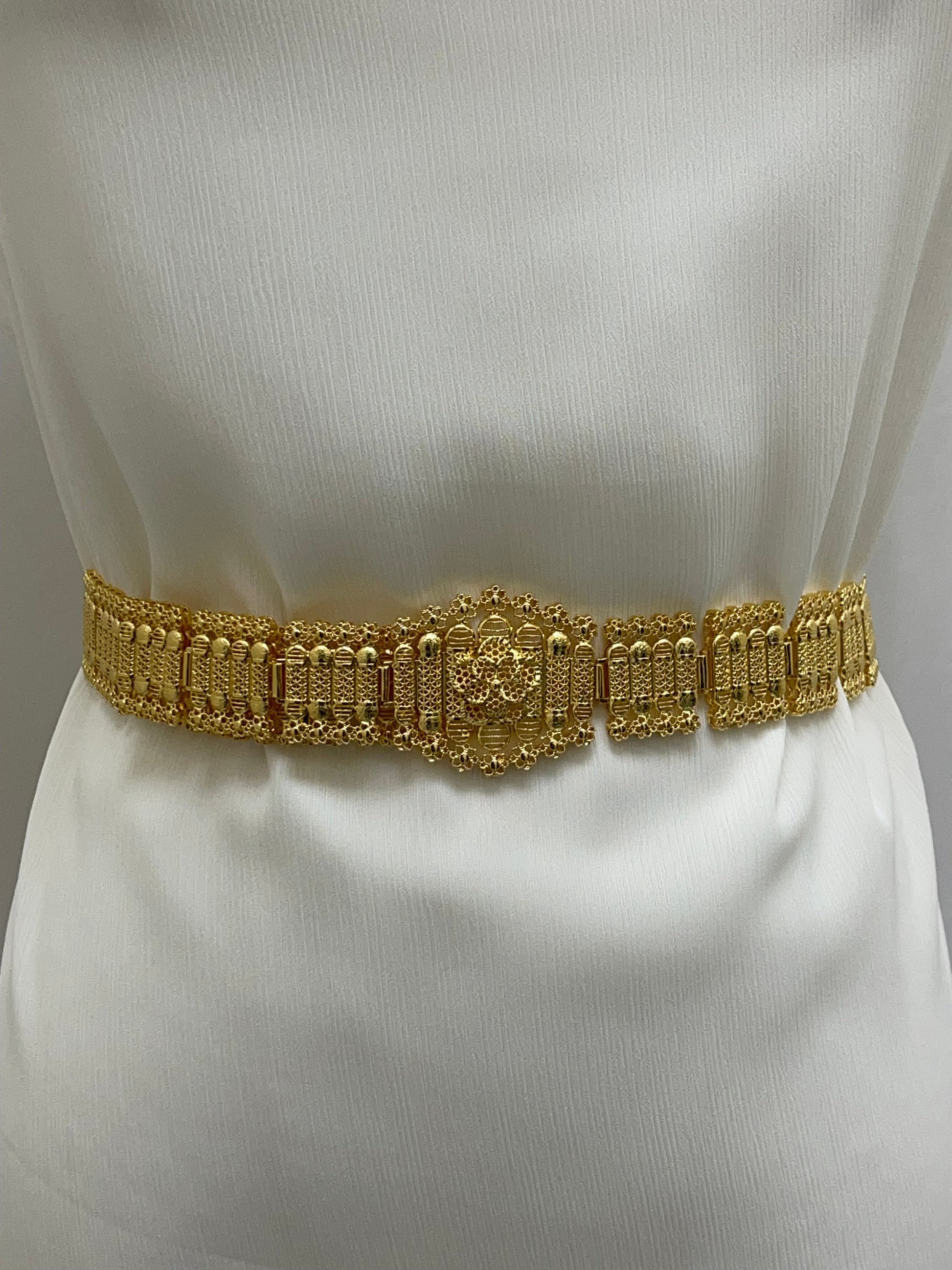 Kurdish gold style belt by Palestinian Elegance on white fabric showcasing intricate gold accessory design