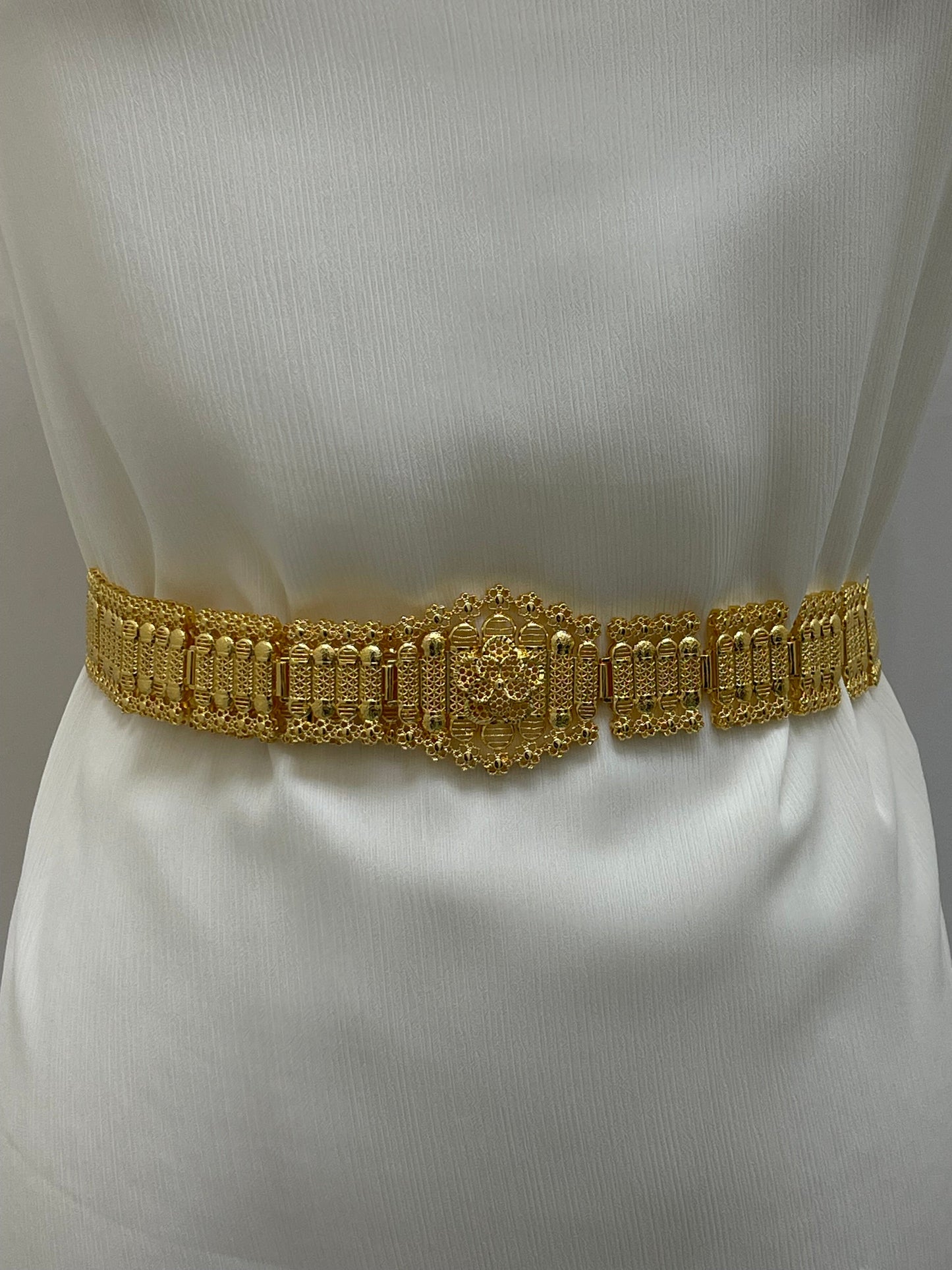 Kurdish gold style belt with intricate designs worn on white fabric from Palestinian Elegance