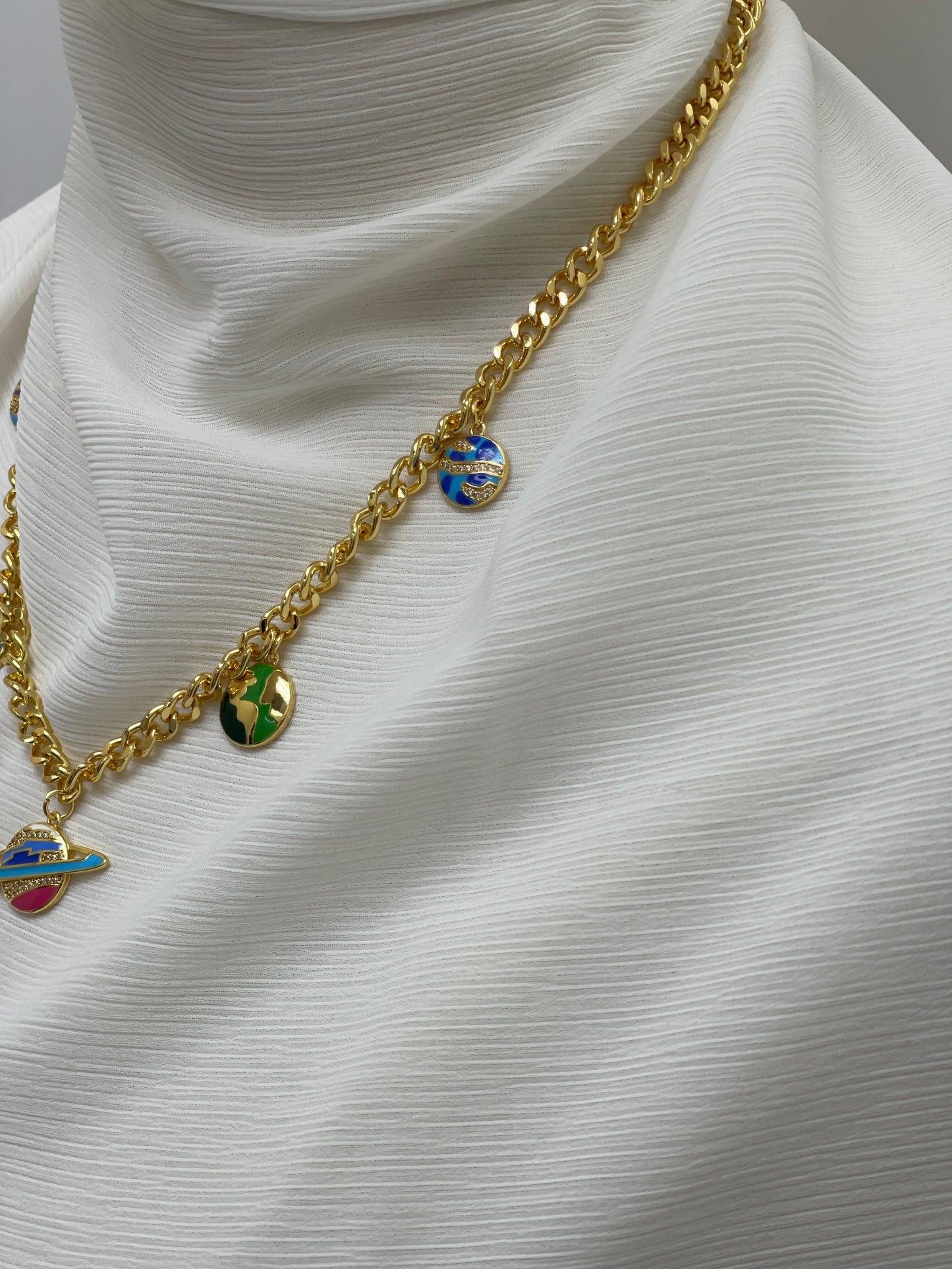Palestinian Elegance gold chain necklace with multicolor planet necklace charms on white fabric