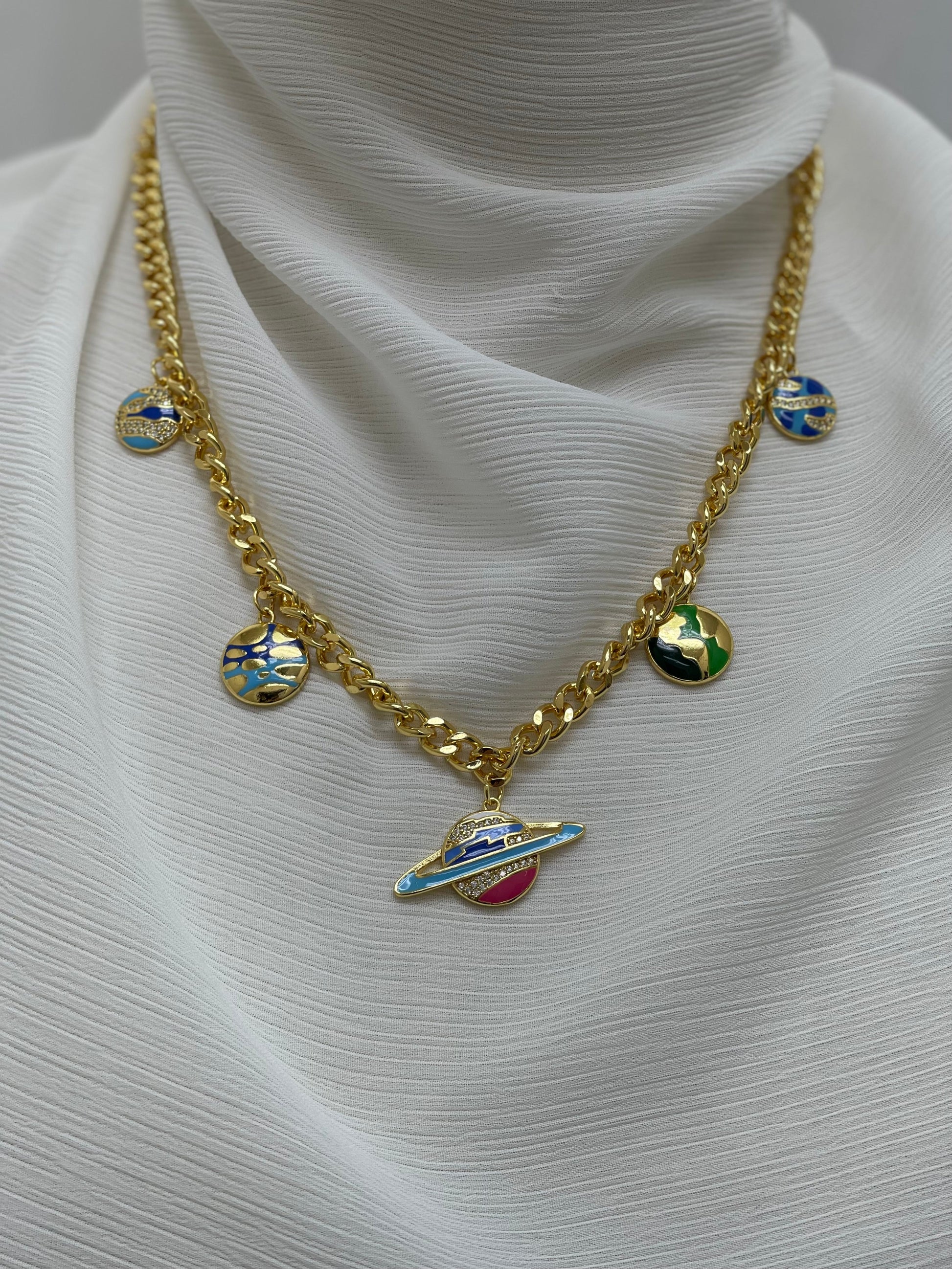 Palestinian Elegance gold chain with multicolor planet necklace and planet charms on white fabric