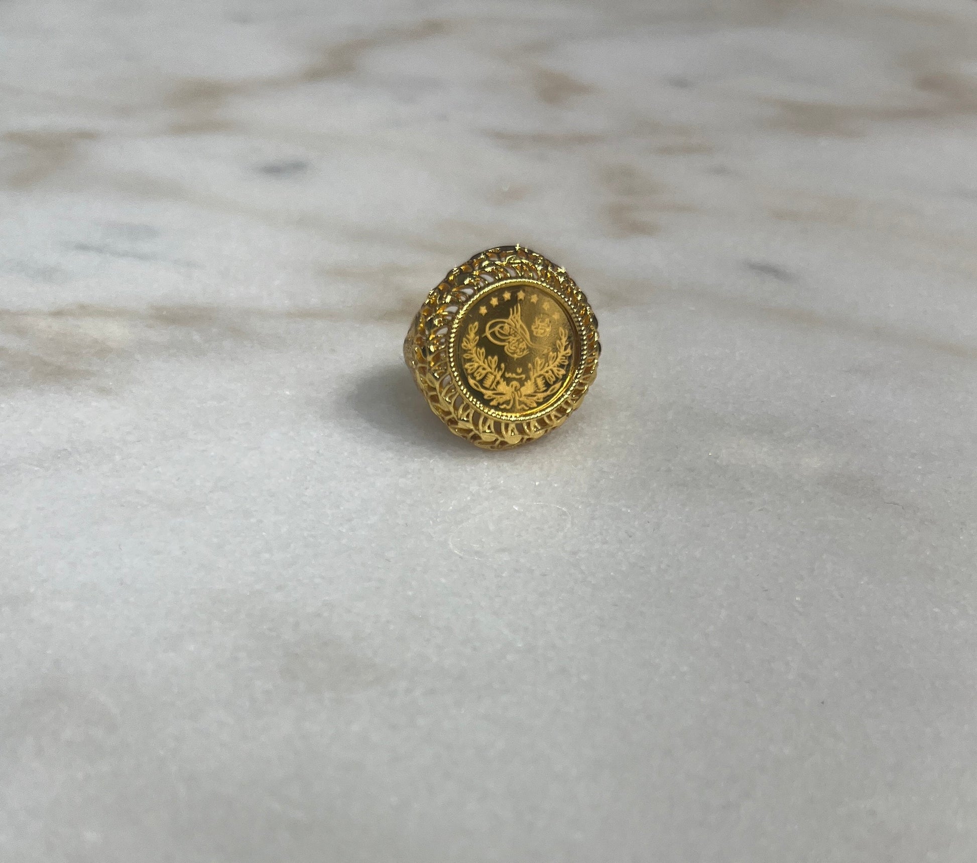 Gold Palestinian coin ring with intricate floral design on marble surface by Palestinian Elegance