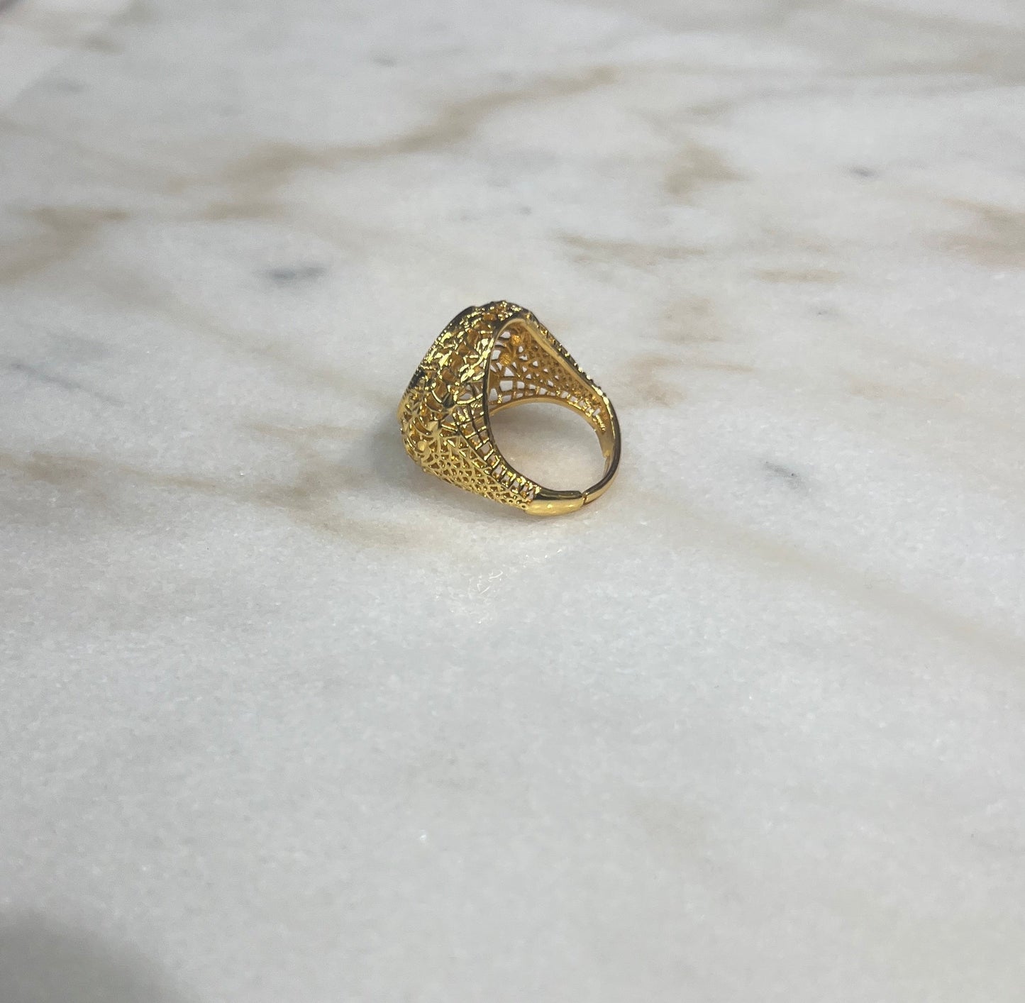 Gold filigree Palestinian coin ring with intricate patterns on a marble surface