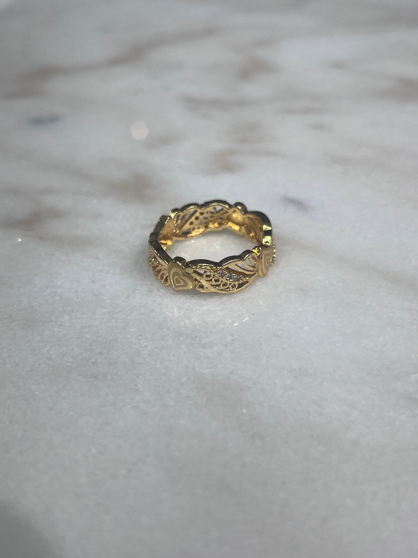 Gold-tone Palestinian embroidered ring with intricate engraved patterns on marble surface