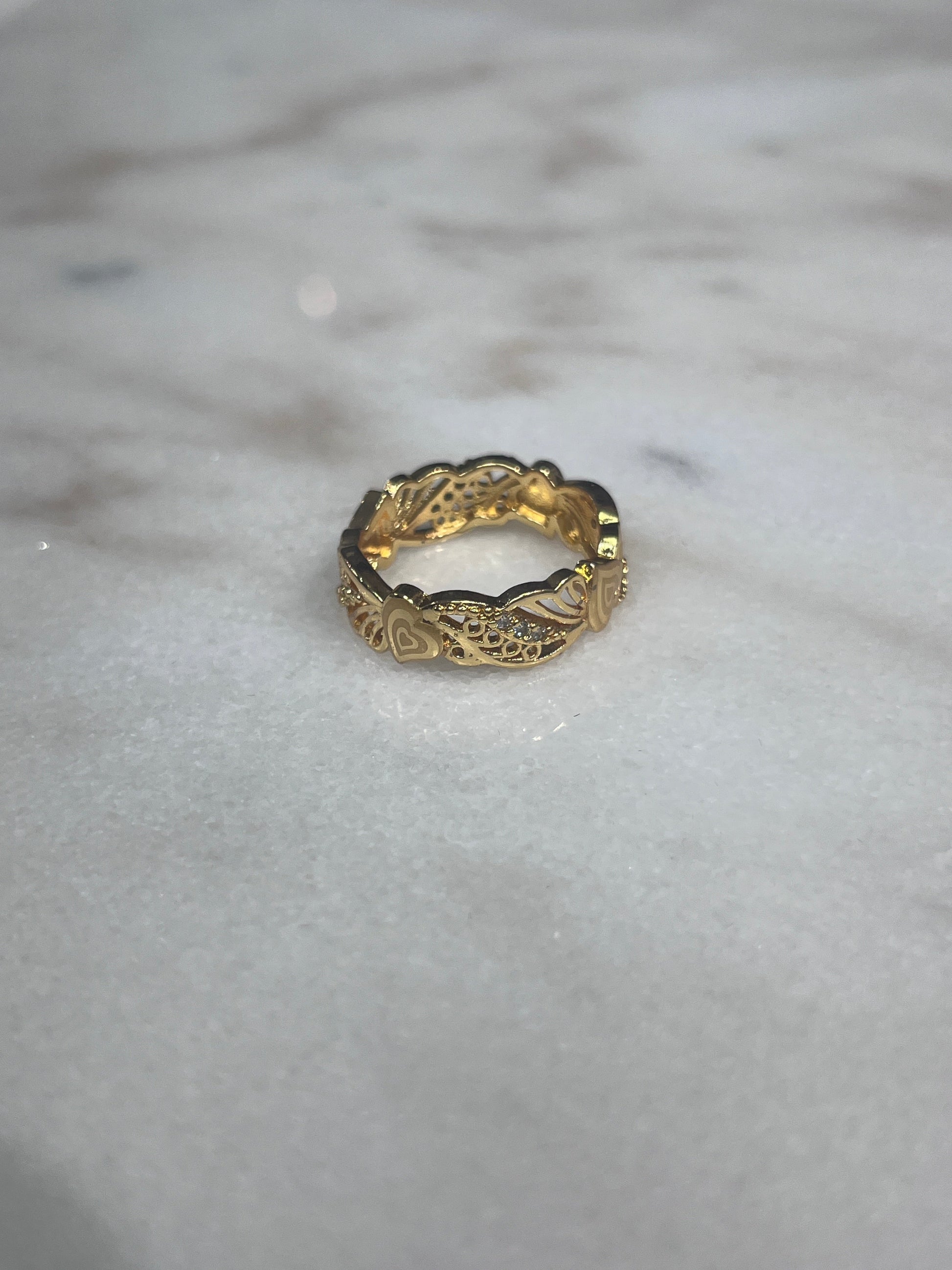 Gold-tone Palestinian embroidered ring with intricate engraved patterns on marble surface