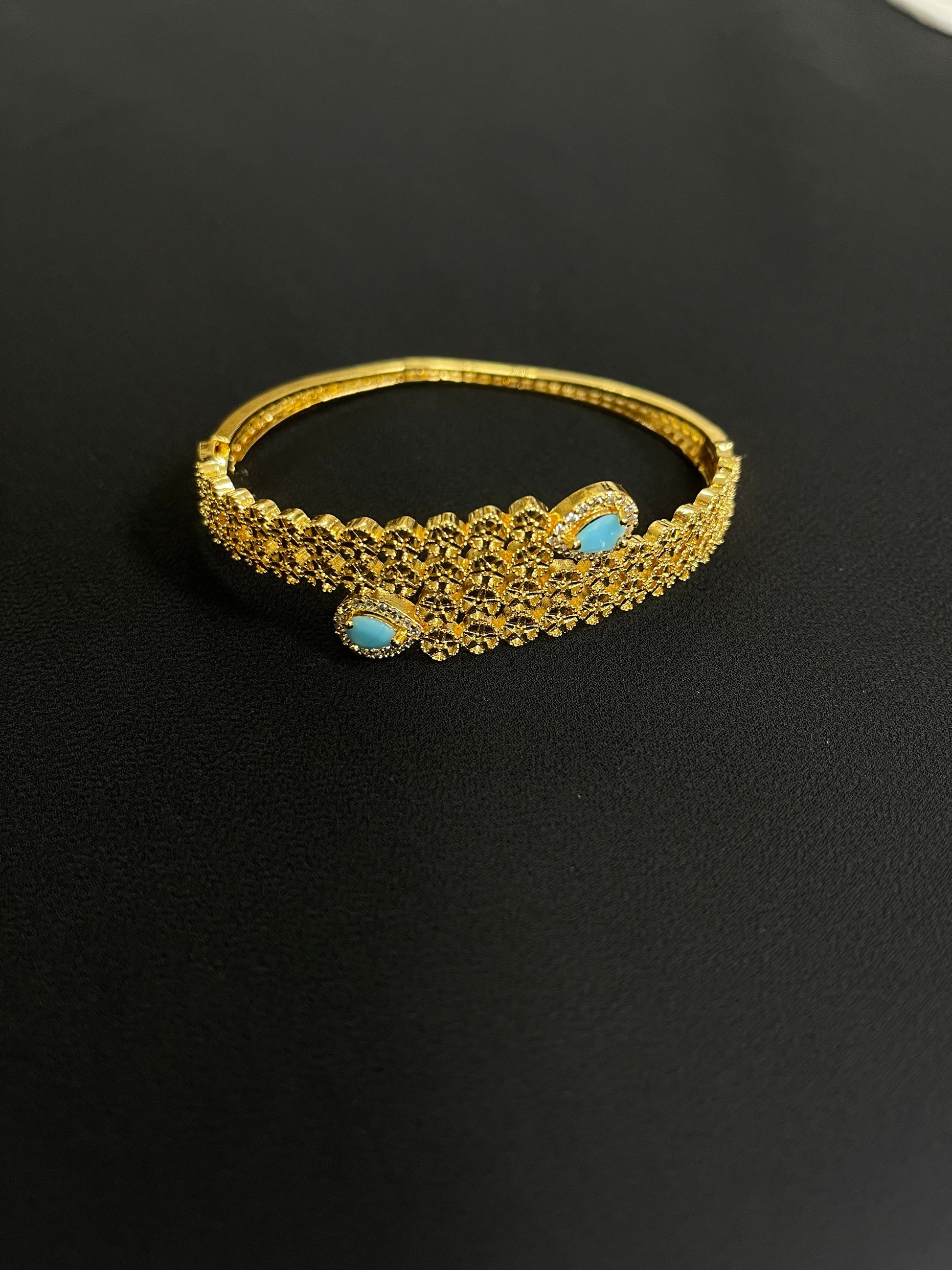 Palestinian gold jewelry set featuring an intricate gold bracelet with turquoise accents on black background