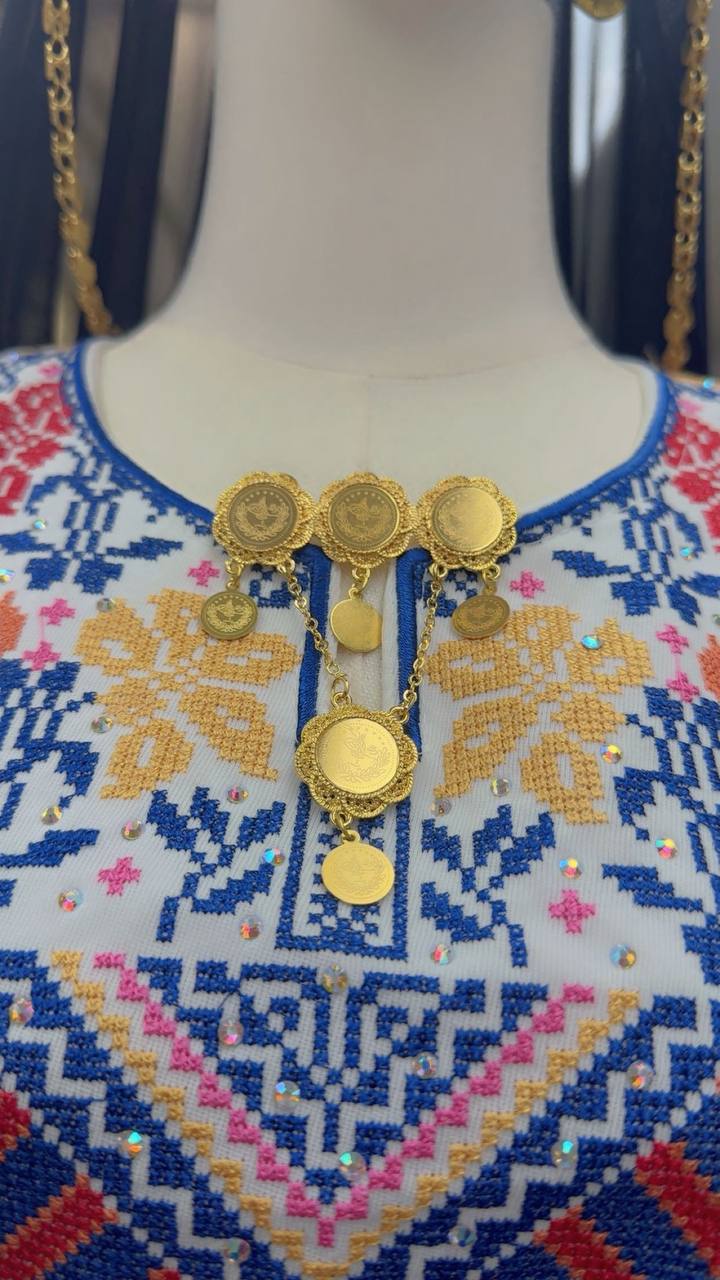 Traditional gold brooch in imitated gold by Palestinian Elegance displayed on embroidered fabric