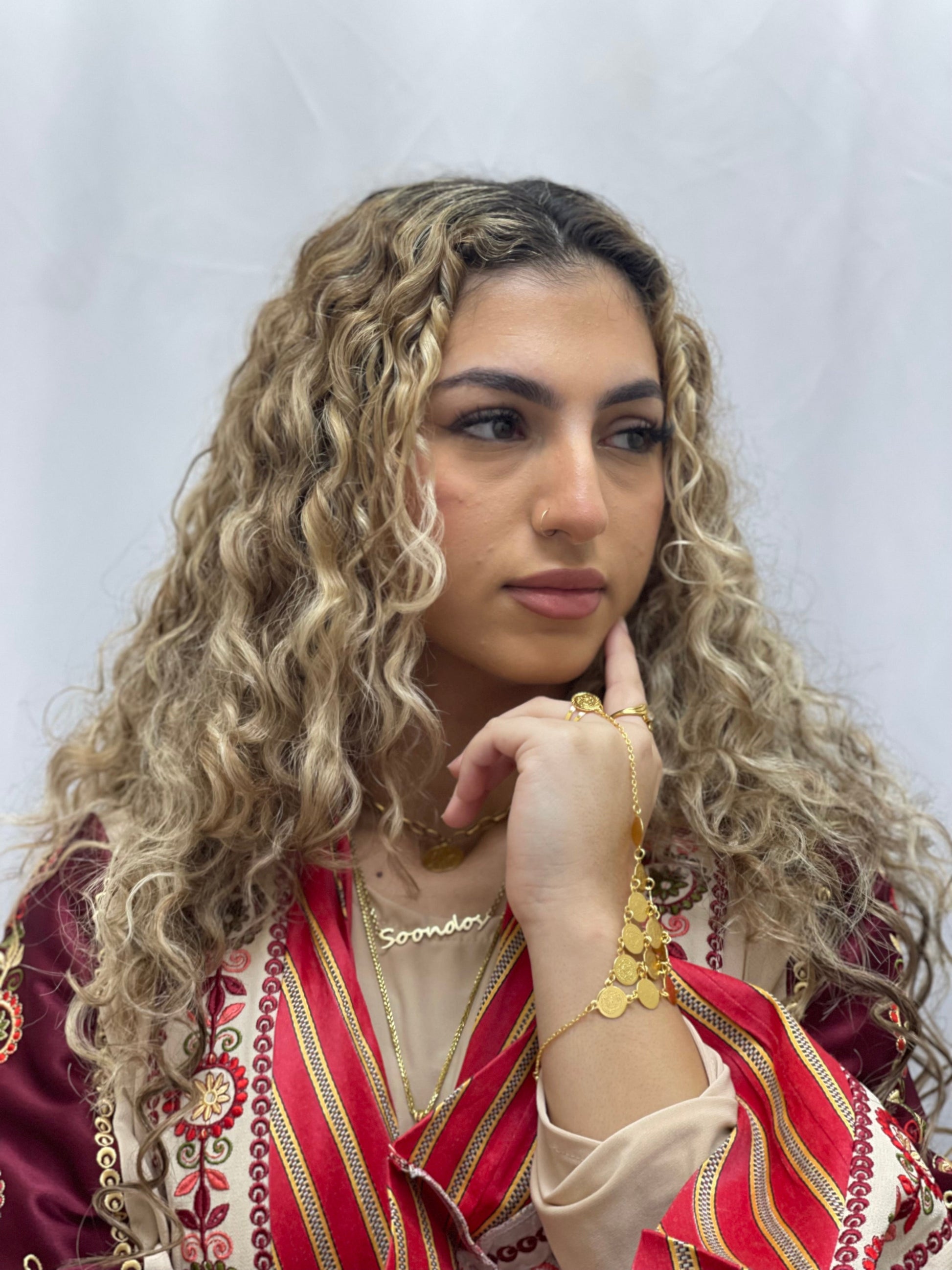 Woman wearing gold kaff hand jewelry and traditional Palestinian attire with curly blonde hair